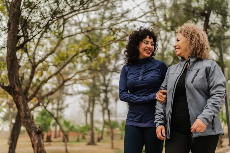 Senior woman walking outdoors with a caregiver
